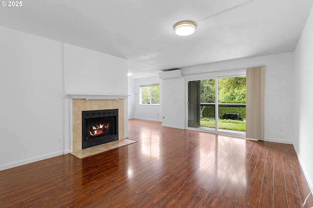 9455 SW 146th Ter Unit D 2, Beaverton, OR 97007 - unfurnished living room featuring an AC wall unit, a tile fireplace, hardwood / wood-style flooring, and baseboards