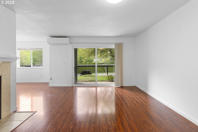 9455 SW 146th Ter Unit D 2, Beaverton, OR 97007 - unfurnished living room featuring a wall unit AC, a fireplace, hardwood / wood-style floors, and baseboards