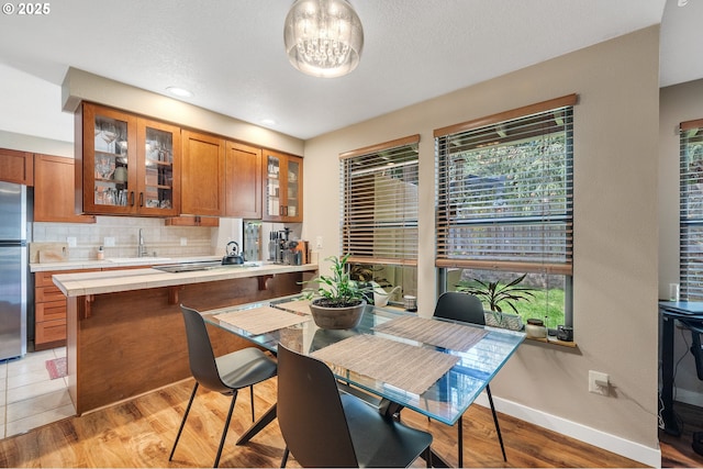 dining room featuring baseboards, a notable chandelier, and light wood finished floors