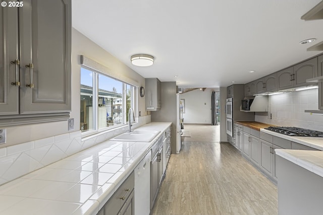 kitchen with sink, gray cabinets, appliances with stainless steel finishes, decorative backsplash, and tile countertops