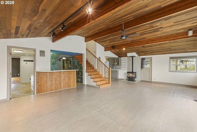 unfurnished living room featuring wood ceiling, hardwood / wood-style flooring, ceiling fan, vaulted ceiling with beams, and a wood stove