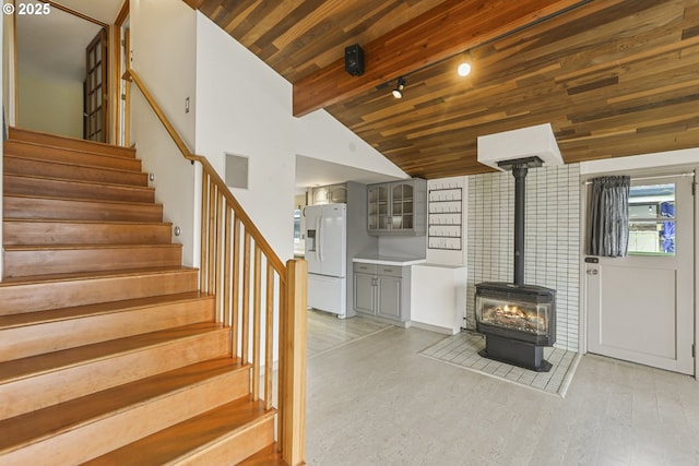 interior space featuring vaulted ceiling with beams, light hardwood / wood-style flooring, wooden ceiling, and a wood stove