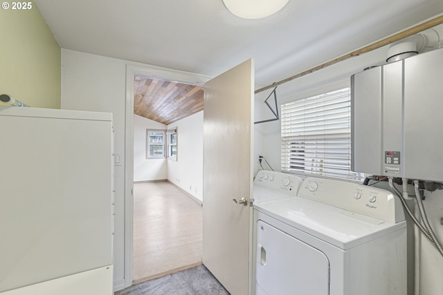 clothes washing area with washer and clothes dryer, light hardwood / wood-style floors, and water heater