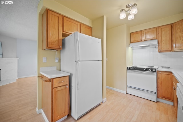 621 SE 121st Ave Unit 29, Vancouver, WA 98683 - kitchen with white appliances, under cabinet range hood, light wood finished floors, tasteful backsplash, and light countertops