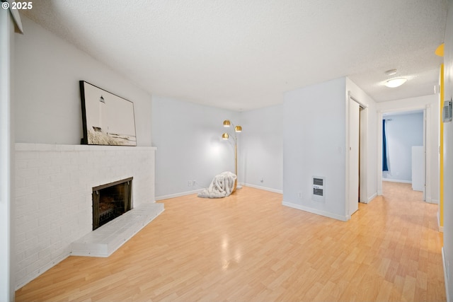 621 SE 121st Ave Unit 29, Vancouver, WA 98683 - unfurnished living room featuring wood finished floors, a fireplace, heating unit, and a textured ceiling