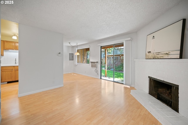 621 SE 121st Ave Unit 29, Vancouver, WA 98683 - unfurnished living room featuring a brick fireplace, a textured ceiling, light wood-type flooring, and electric panel