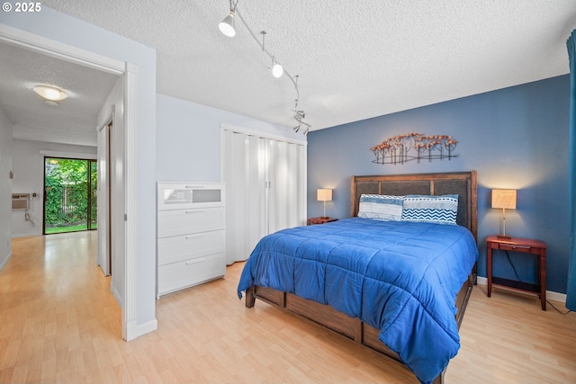 621 SE 121st Ave Unit 29, Vancouver, WA 98683 - bedroom featuring light wood-style flooring, a textured ceiling, a closet, a wall mounted AC, and rail lighting