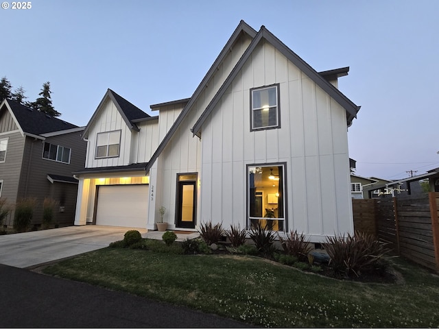 modern farmhouse featuring board and batten siding, concrete driveway, fence, and a garage