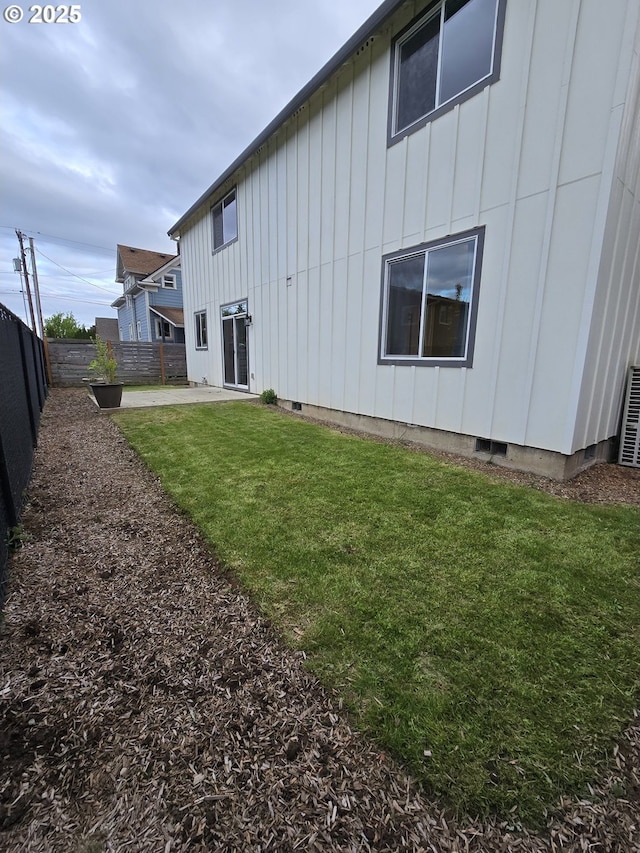 rear view of property featuring fence, a patio, board and batten siding, crawl space, and a yard