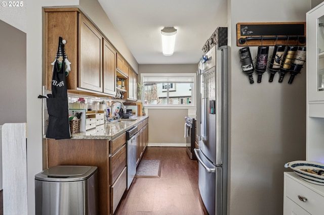 kitchen featuring sink, dark hardwood / wood-style flooring, decorative backsplash, stainless steel appliances, and light stone countertops