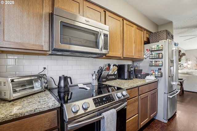 kitchen featuring stainless steel appliances, dark hardwood / wood-style floors, backsplash, and light stone counters