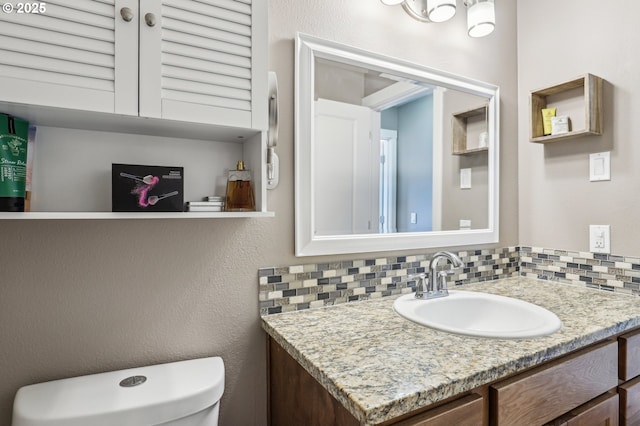 bathroom featuring vanity, toilet, and decorative backsplash