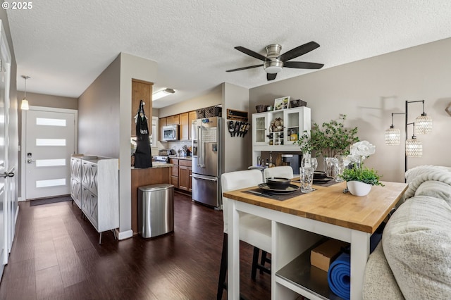 living area with dark wood-style floors, ceiling fan, and baseboards