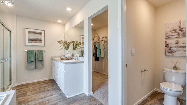 bathroom featuring hardwood / wood-style flooring, vanity, toilet, and a shower with door