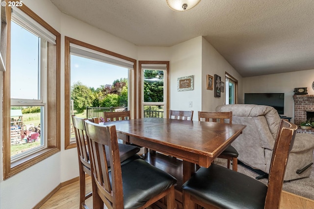 30174 SE Waybill Rd, Boring, OR 97009 - dining room featuring light wood-type flooring, plenty of natural light, a textured ceiling, a brick fireplace, and baseboards