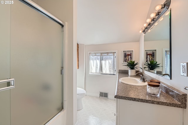 bathroom featuring toilet, vanity, and a shower with door