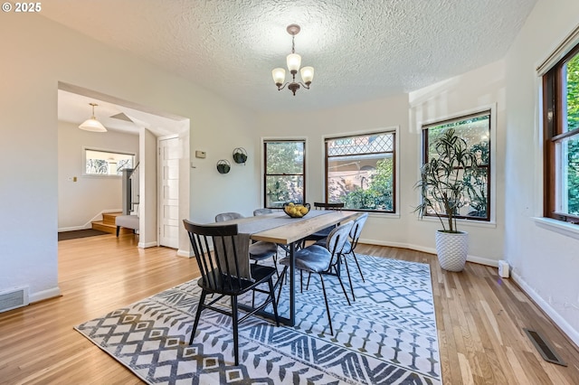 dining area with an inviting chandelier, hardwood / wood-style flooring, and a textured ceiling