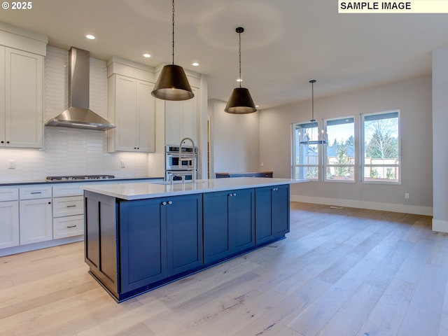 10216 NW Lee St, Portland, OR 97229 - kitchen featuring wall chimney range hood, baseboards, light wood-style floors, tasteful backsplash, and white cabinetry