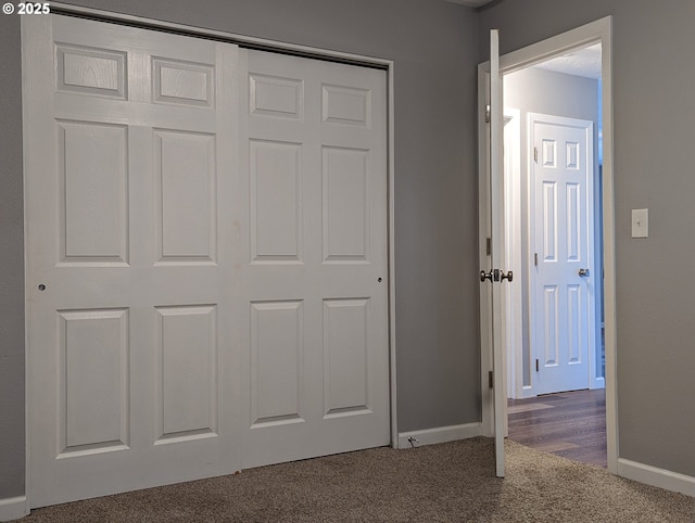 unfurnished bedroom with a closet and dark colored carpet