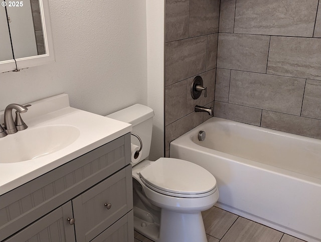 full bathroom featuring hardwood / wood-style flooring, vanity, tiled shower / bath, and toilet