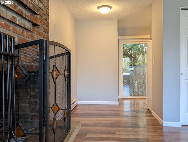 hallway featuring dark wood-type flooring, baseboard heating, and a textured ceiling