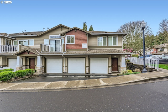 14700 SW Sandhill Loop Unit 204, Beaverton, OR 97007 - view of front of property with a garage, asphalt driveway, stone siding, a shingled roof, and a balcony