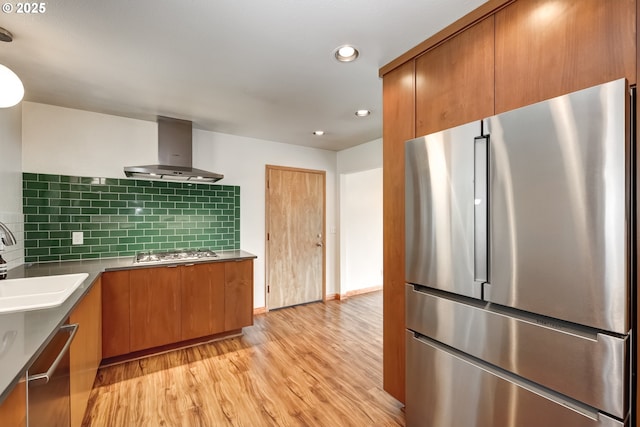 14075 SW Cherryhill Dr, Beaverton, OR 97008 - kitchen with light wood-style floors, appliances with stainless steel finishes, brown cabinetry, and wall chimney exhaust hood