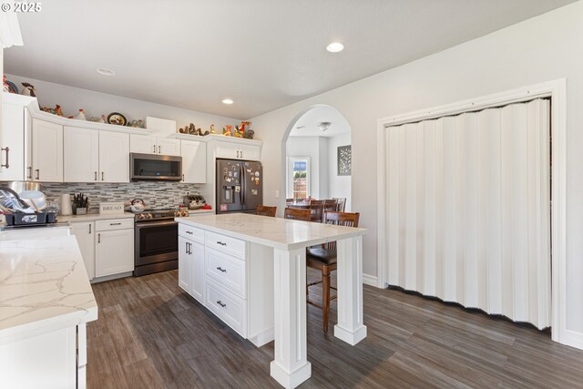 227 Hauser Ct, Molalla, OR 97038 - kitchen with appliances with stainless steel finishes, dark wood-style flooring, arched walkways, a kitchen bar, and recessed lighting