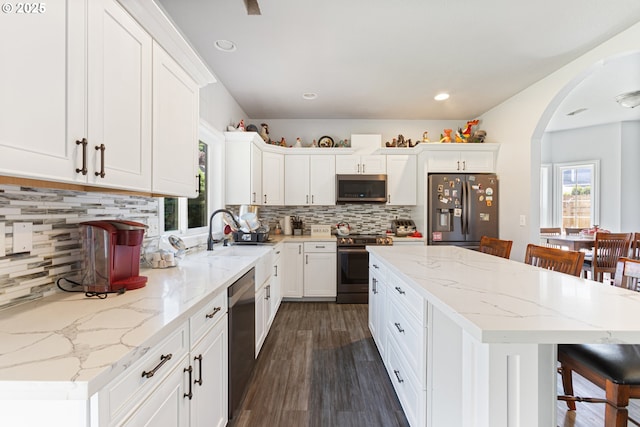 227 Hauser Ct, Molalla, OR 97038 - kitchen featuring stainless steel appliances, white cabinetry, a center island, a kitchen bar, and dark wood-style floors