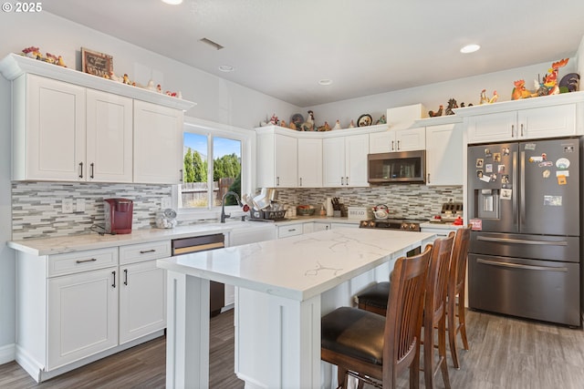227 Hauser Ct, Molalla, OR 97038 - kitchen with stainless steel appliances, wood finished floors, white cabinetry, a center island, and recessed lighting