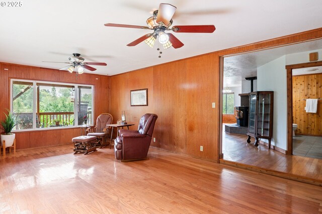 11754 Colvin Rd, Clatskanie, OR 97016 - sitting room featuring wood finished floors, wood walls, a ceiling fan, a wood stove, and baseboards
