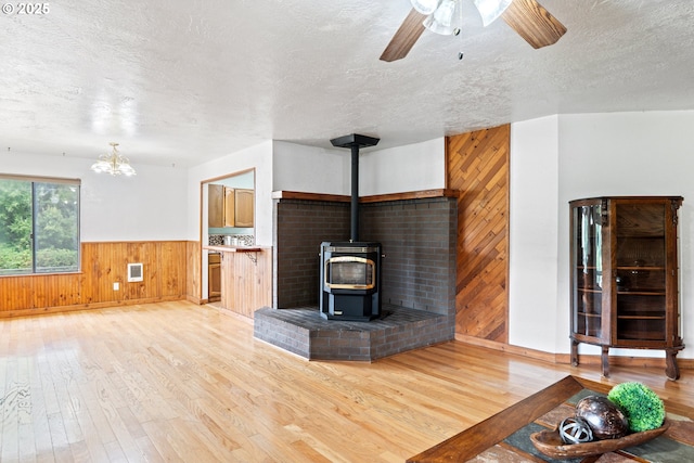 11754 Colvin Rd, Clatskanie, OR 97016 - unfurnished living room featuring wood walls, a textured ceiling, light wood-style flooring, a wood stove, and a wainscoted wall