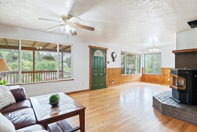 11754 Colvin Rd, Clatskanie, OR 97016 - living area featuring a wood stove, wood-type flooring, wainscoting, wooden walls, and a chandelier