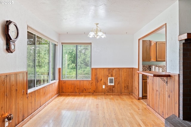 11754 Colvin Rd, Clatskanie, OR 97016 - unfurnished dining area featuring light wood-style floors, wainscoting, a chandelier, wooden walls, and a textured ceiling