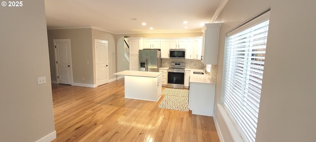 2659 SW Latourell Pl SW, Troutdale, OR 97060 - kitchen with stainless steel appliances, crown molding, a center island, light countertops, and light wood finished floors