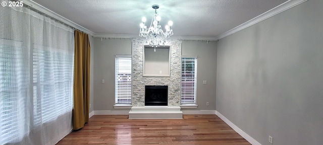 2659 SW Latourell Pl SW, Troutdale, OR 97060 - unfurnished living room with crown molding, a chandelier, wood finished floors, a stone fireplace, and baseboards
