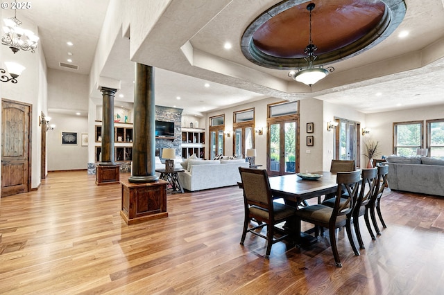 1025 Echo Dr, Roseburg, OR 97470 - dining space featuring light wood-style flooring, decorative columns, recessed lighting, a stone fireplace, and a tray ceiling
