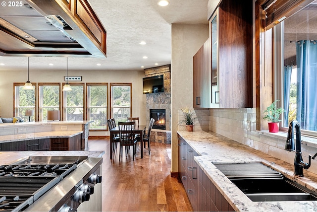 1025 Echo Dr, Roseburg, OR 97470 - kitchen with wood finished floors, recessed lighting, a stone fireplace, light stone countertops, and exhaust hood