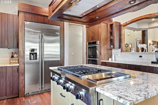 1025 Echo Dr, Roseburg, OR 97470 - kitchen with appliances with stainless steel finishes, tasteful backsplash, light stone counters, and wood finished floors