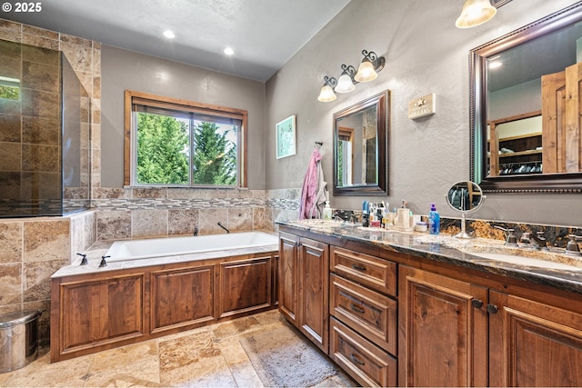 1025 Echo Dr, Roseburg, OR 97470 - bathroom with a garden tub, double vanity, stone tile floors, recessed lighting, and a textured wall