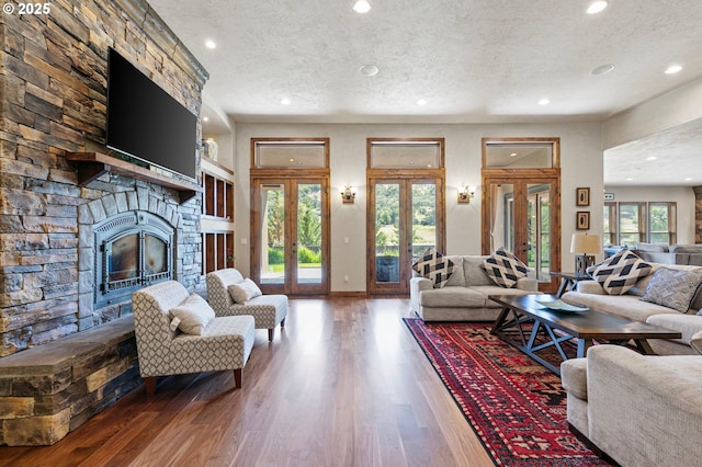 1025 Echo Dr, Roseburg, OR 97470 - living area with french doors, a textured ceiling, recessed lighting, a stone fireplace, and wood finished floors