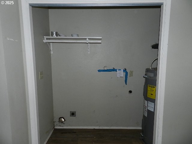 laundry room with electric water heater, dark wood-type flooring, and electric dryer hookup