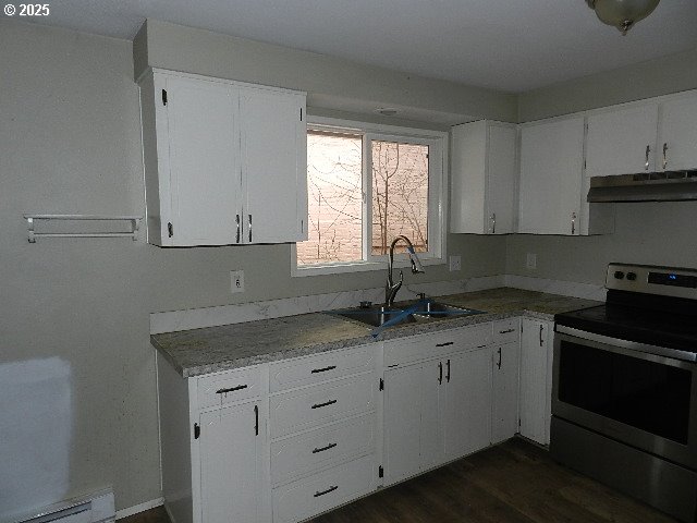 kitchen with sink, white cabinets, baseboard heating, and stainless steel electric range