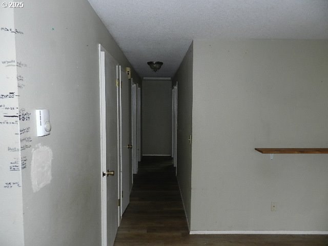 corridor featuring a textured ceiling and dark hardwood / wood-style flooring