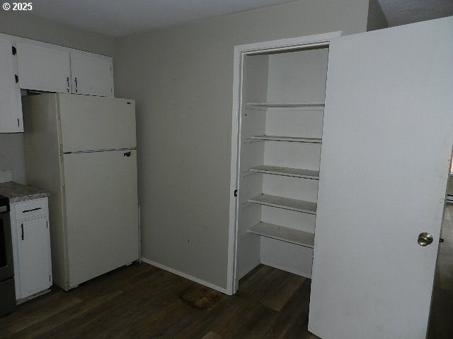 kitchen with dark hardwood / wood-style flooring, white refrigerator, and white cabinetry