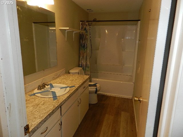 full bathroom featuring toilet, shower / bath combo, wood-type flooring, and vanity