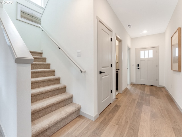 foyer with light wood-style floors, stairway, and baseboards