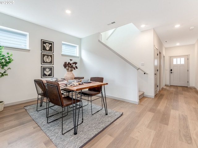 dining room with stairway, light wood-type flooring, visible vents, and baseboards