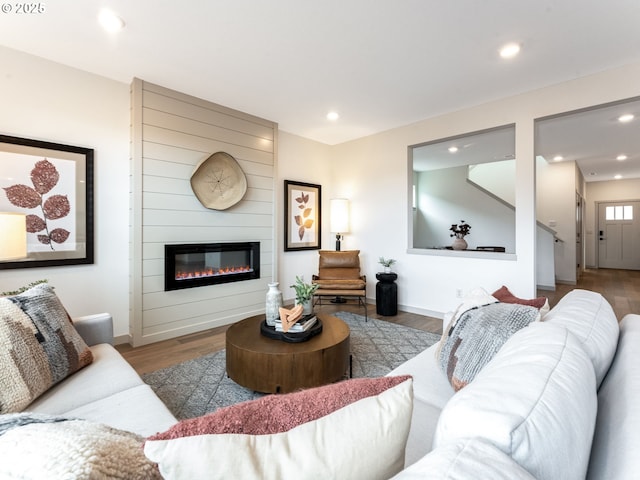 living area with recessed lighting, a large fireplace, baseboards, and wood finished floors