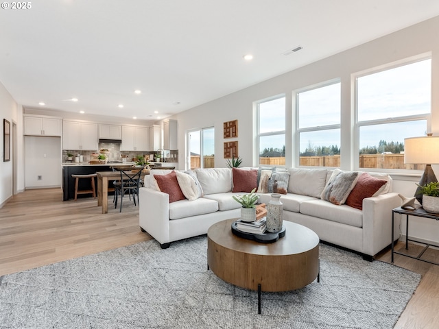 living room featuring light wood-style floors, visible vents, and recessed lighting